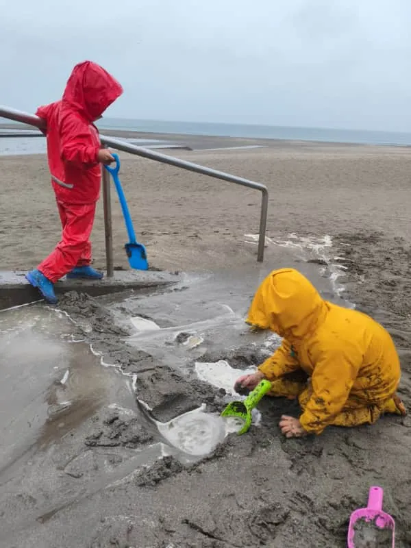 レインウェアで砂遊びをする子どもたち