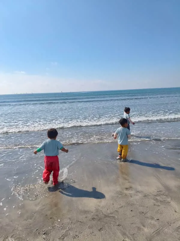 海辺で波と遊ぶ子どもたち