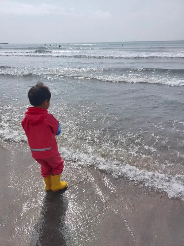 海岸で波を見つめる子ども