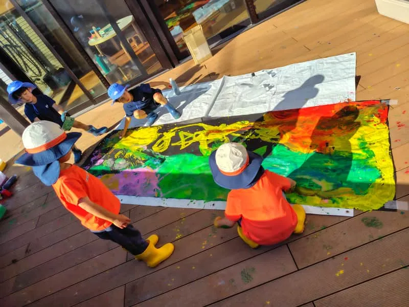 テラスでダイナミックに絵を描く子どもたち